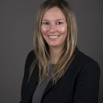 Smiling person in a dark blazer, portrait.