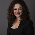 Smiling woman with curly hair, black attire.