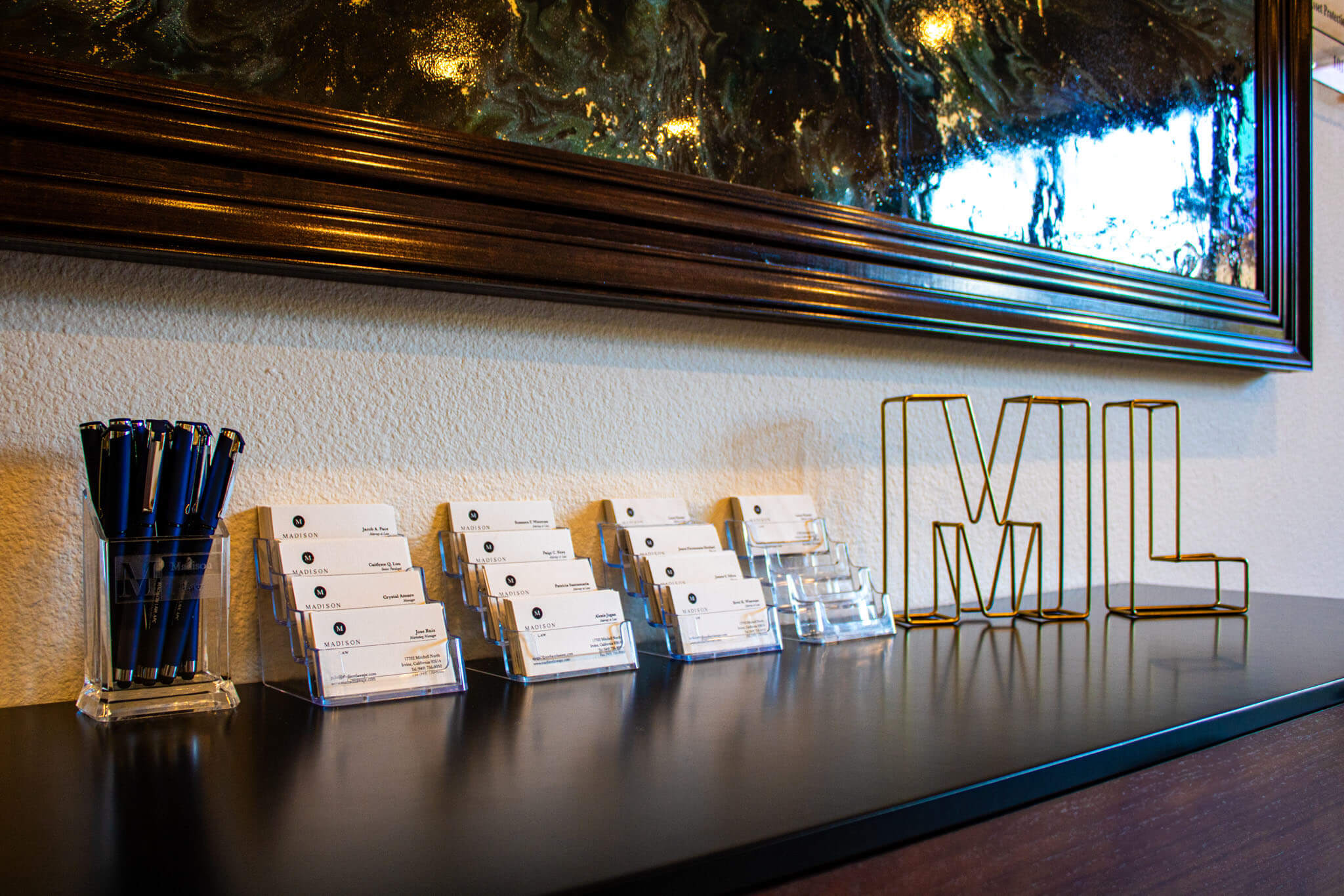 Display of business cards and a decorative metal "MI" on a dark surface under a mirror.