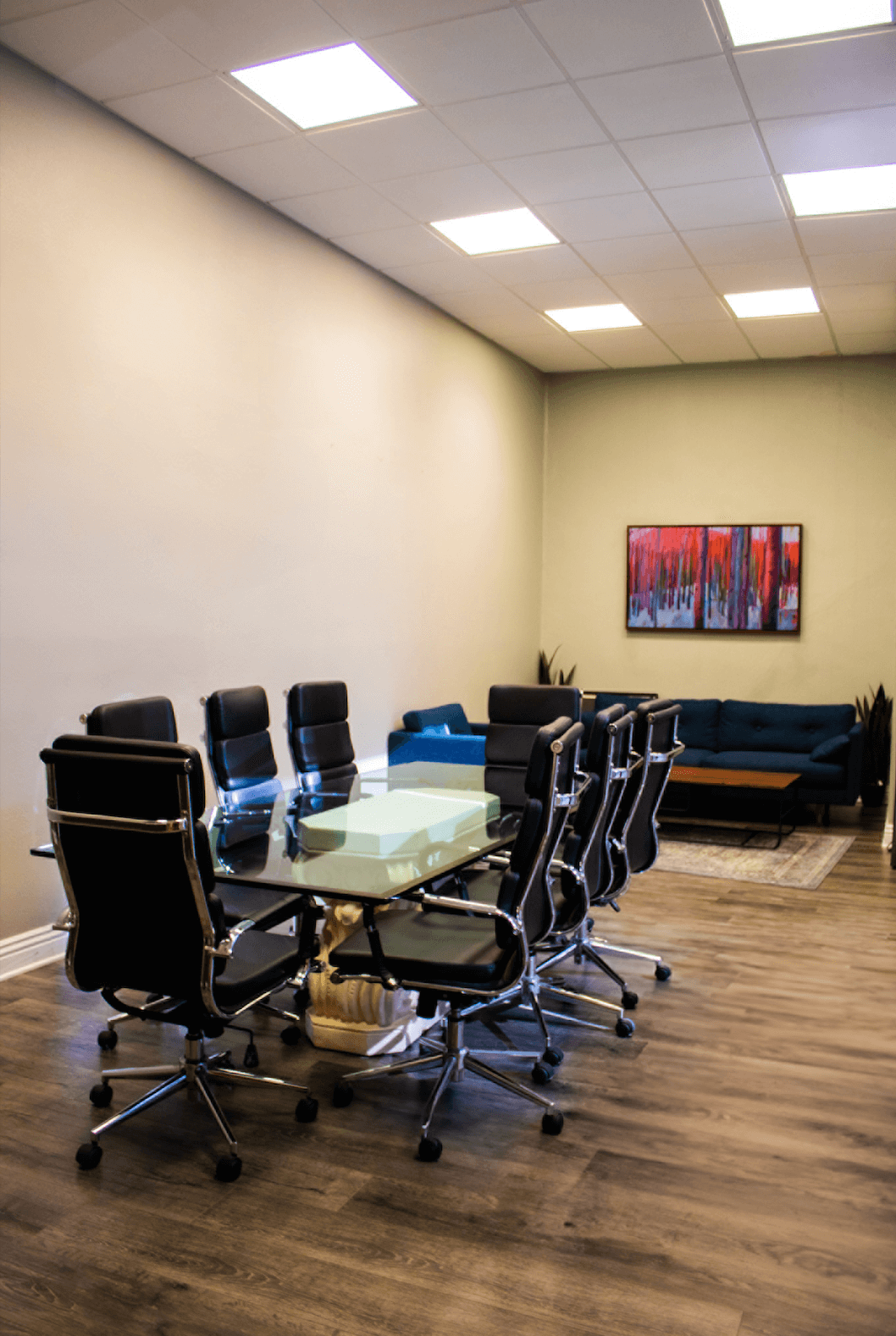 Modern conference room with glass table and black chairs.