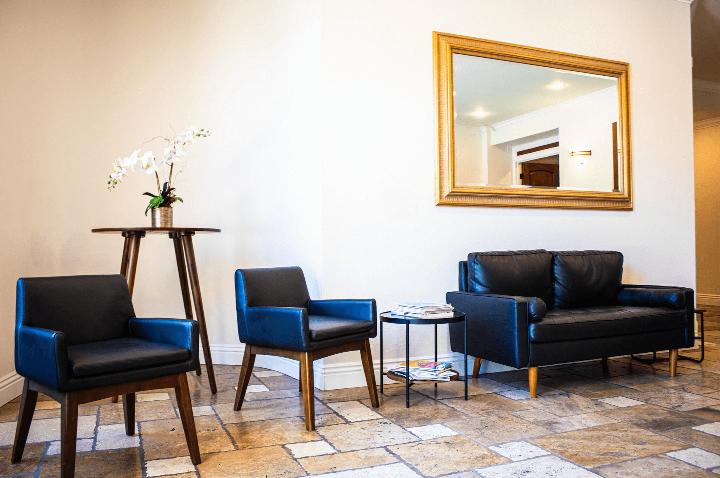 Modern waiting room with blue chairs and a large mirror on the wall.