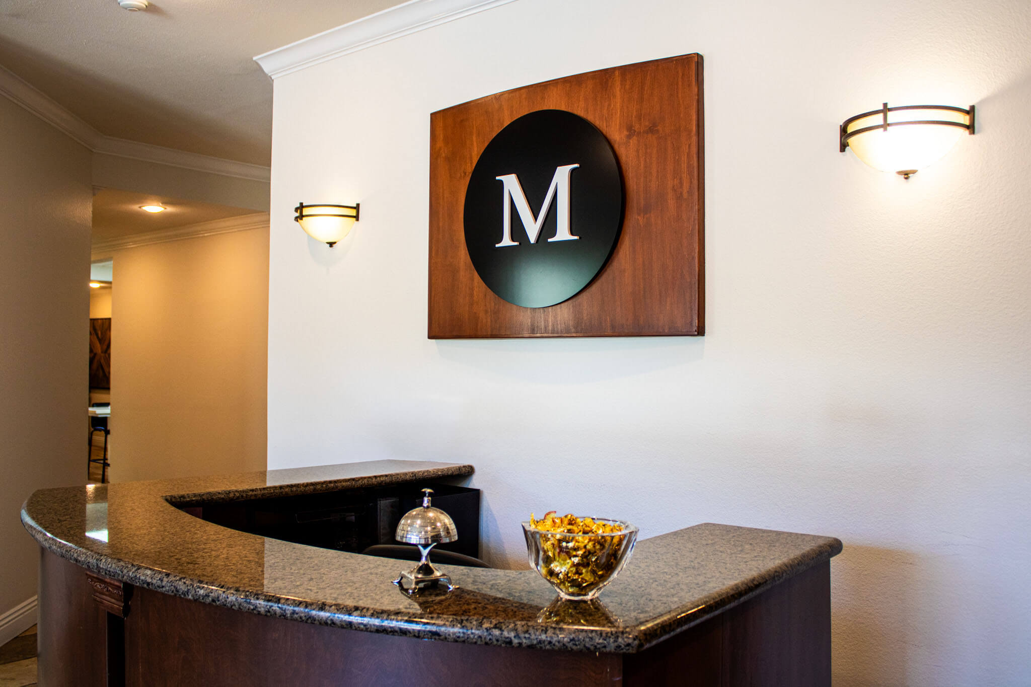 Elegant hotel reception with a stylish 'M' logo and decorative lighting.