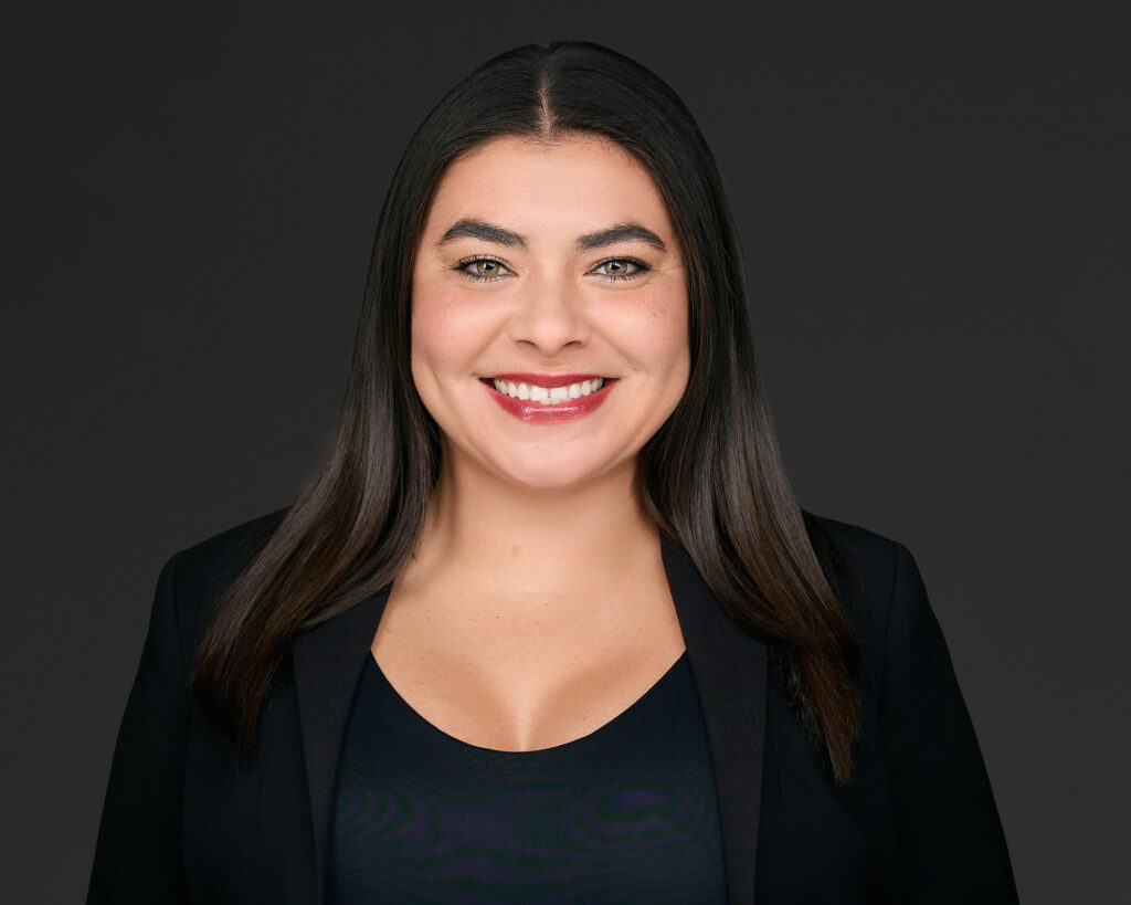 Professional headshot of a smiling woman with dark hair in business attire.