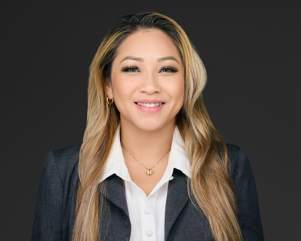 Professional woman smiling in corporate attire against a dark background.