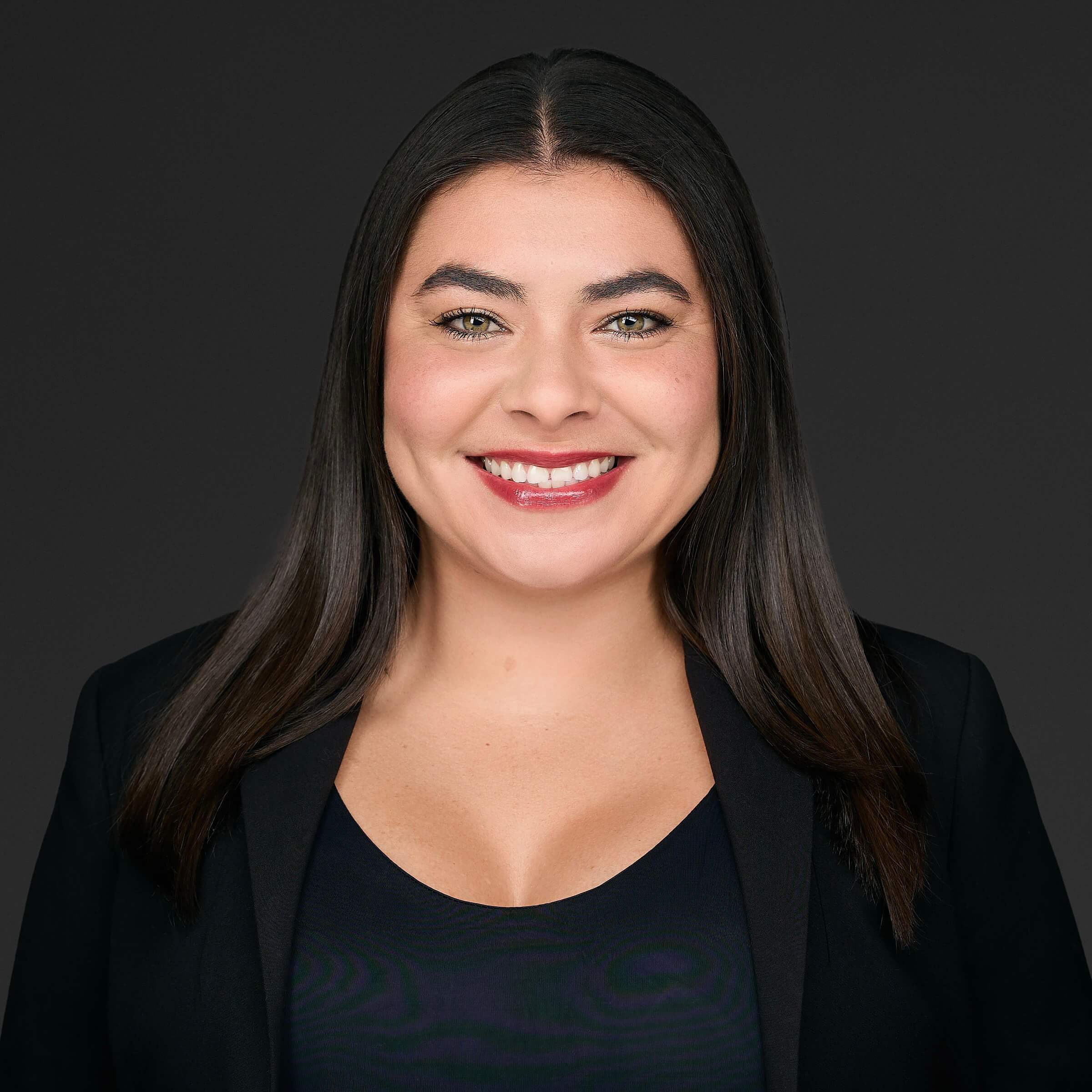 Professional headshot of a smiling woman with dark hair against a black background.