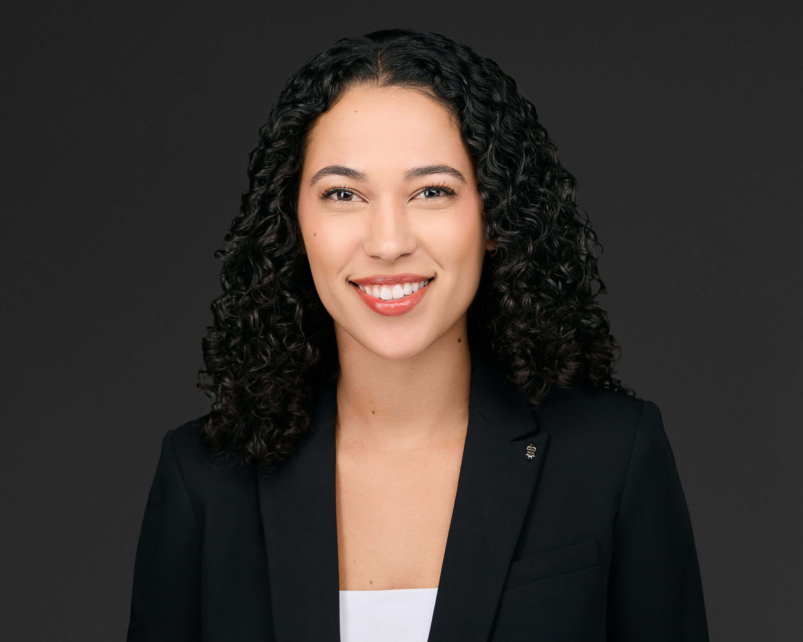 Professional headshot of Alexis A. Jugan, Esq., Associate at Madison Law, in a white blouse and black suit jacket, smiling confidently.