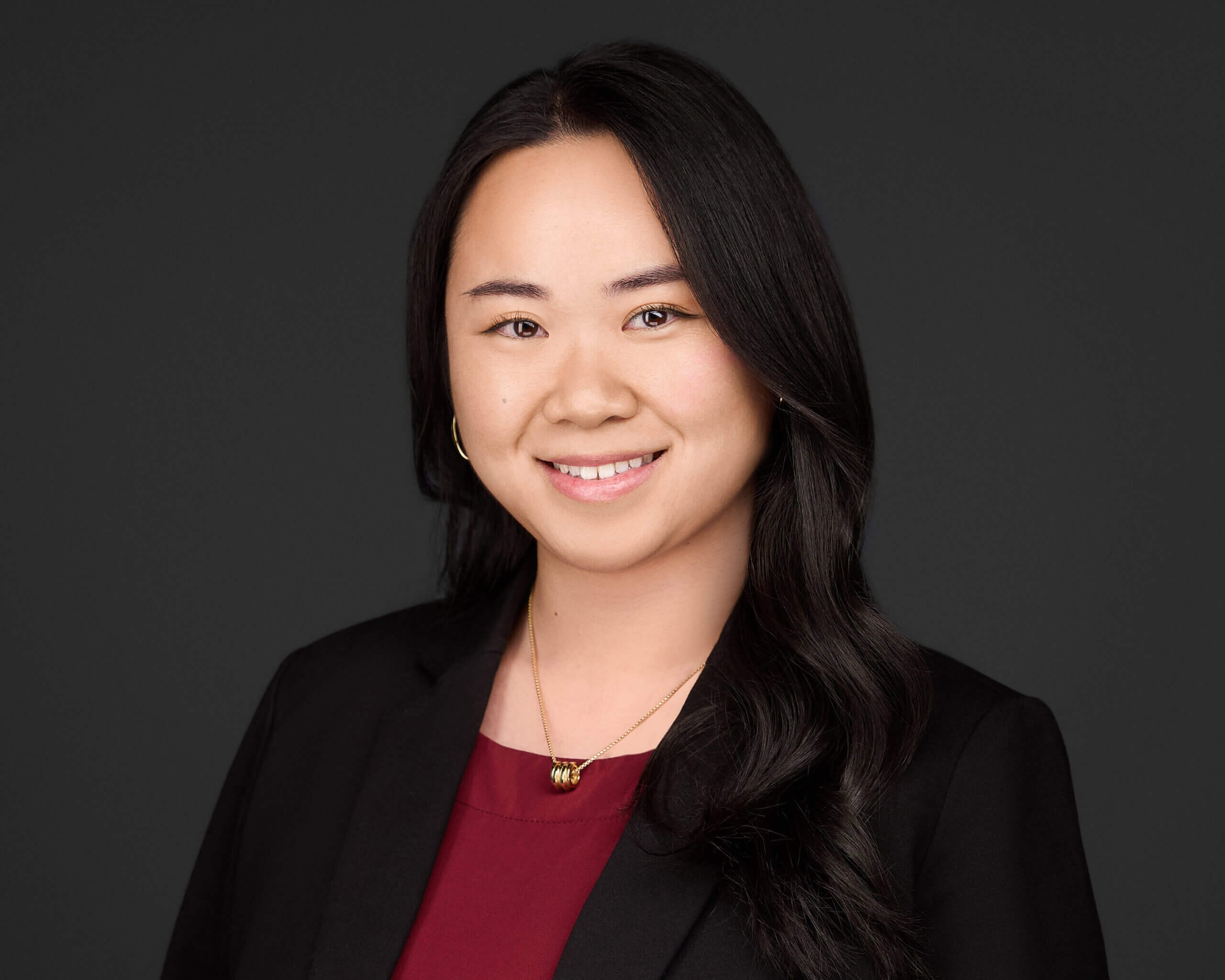Professional headshot of Callie K. Yu, Esq., associate attorney at Madison Law, in a black suit and burgundy blouse, smiling confidently.